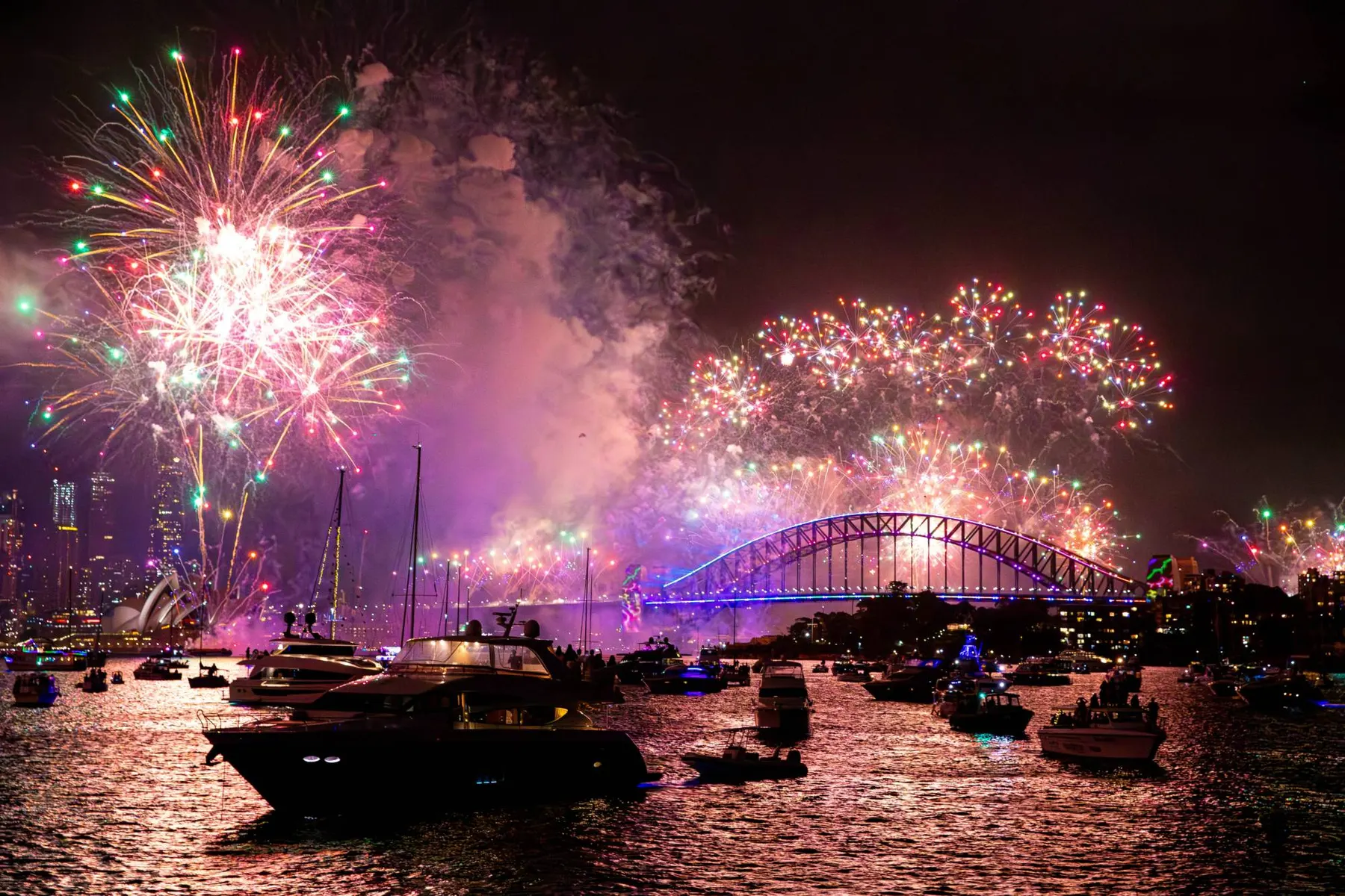 Midnight fireworks over the Harbour Bridge and the Opera House, seen from a boat among the fleet on the water