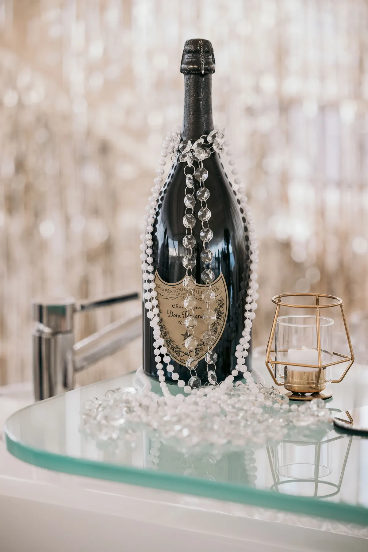 A bottle of Dom Pérignon draped in pearls on the bar