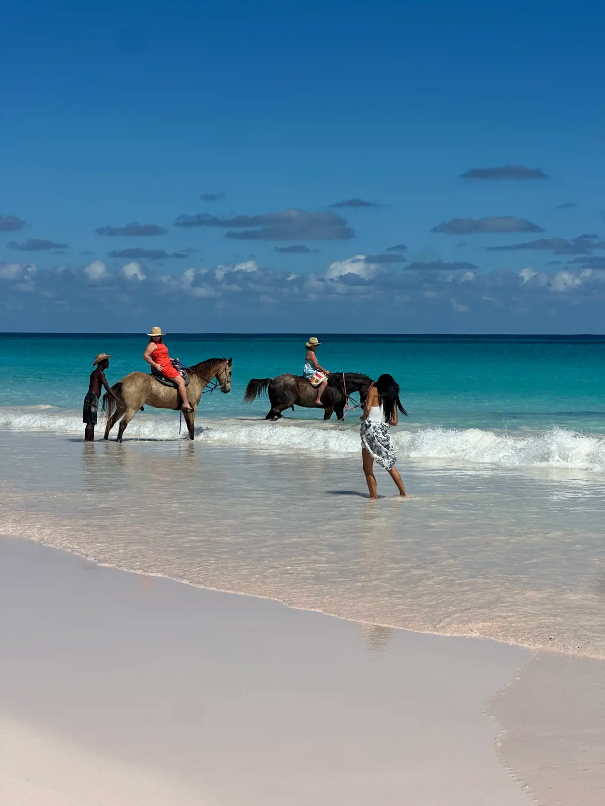 Two riders on horses in the surf on Pink Sands Beach