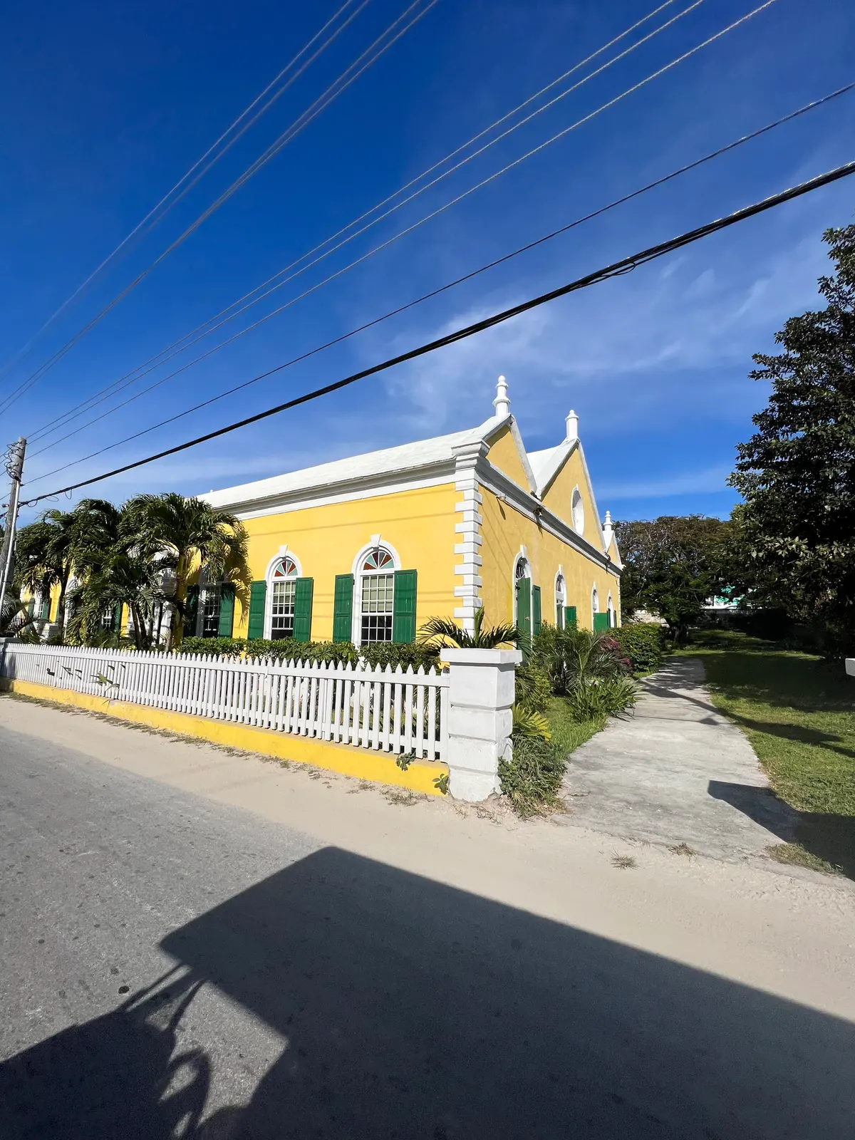 The yellow church with green shutters behind a white picket fence